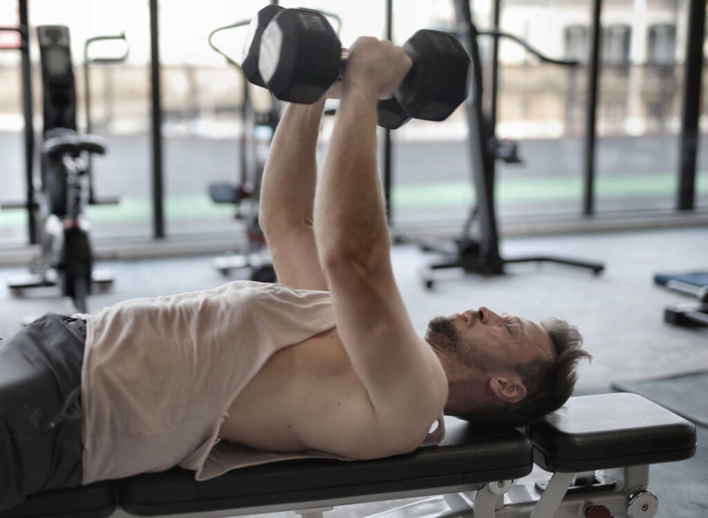 Person performing dumbbell exercise in bright gym space