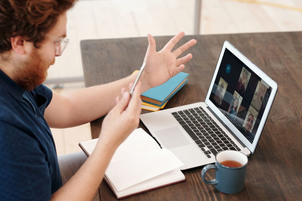 Person on video call with fitness coach on laptop screen during workout