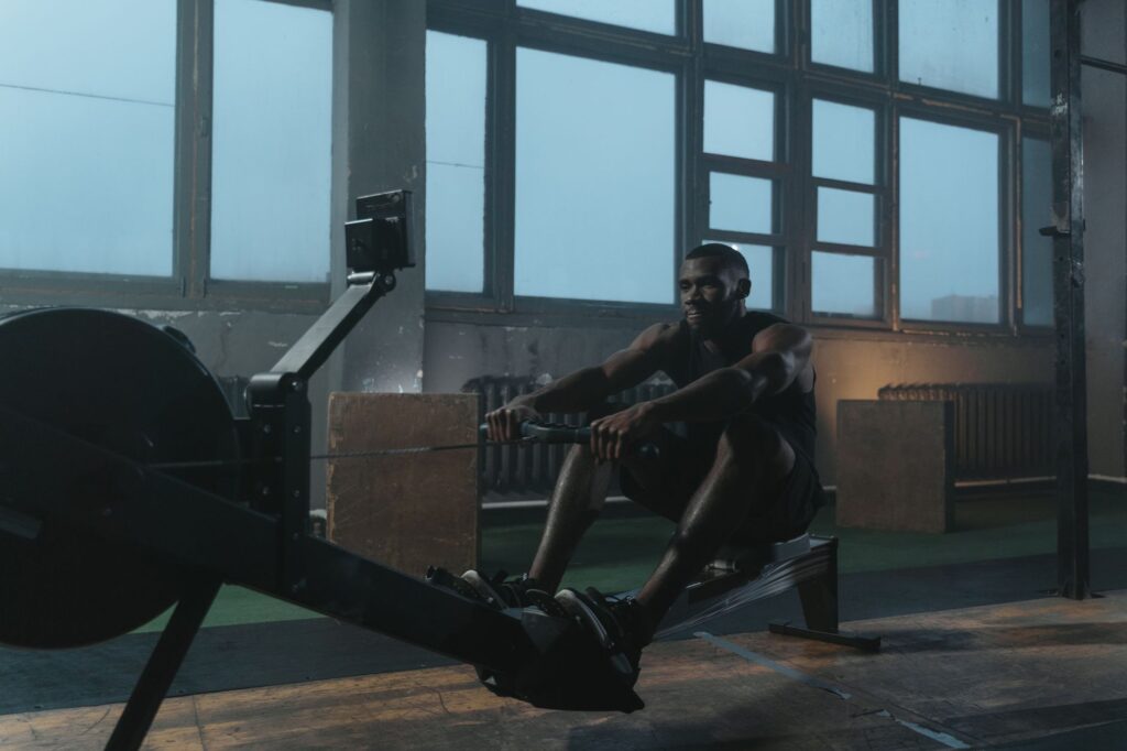 Person rowing on machine in well-equipped gym environment